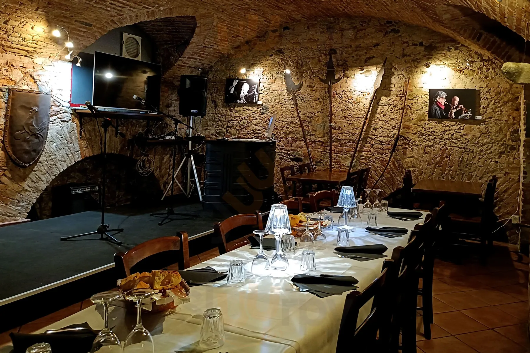 La sala di ACCASA, con volte in mattoni, tavoli apparecchiati e palco